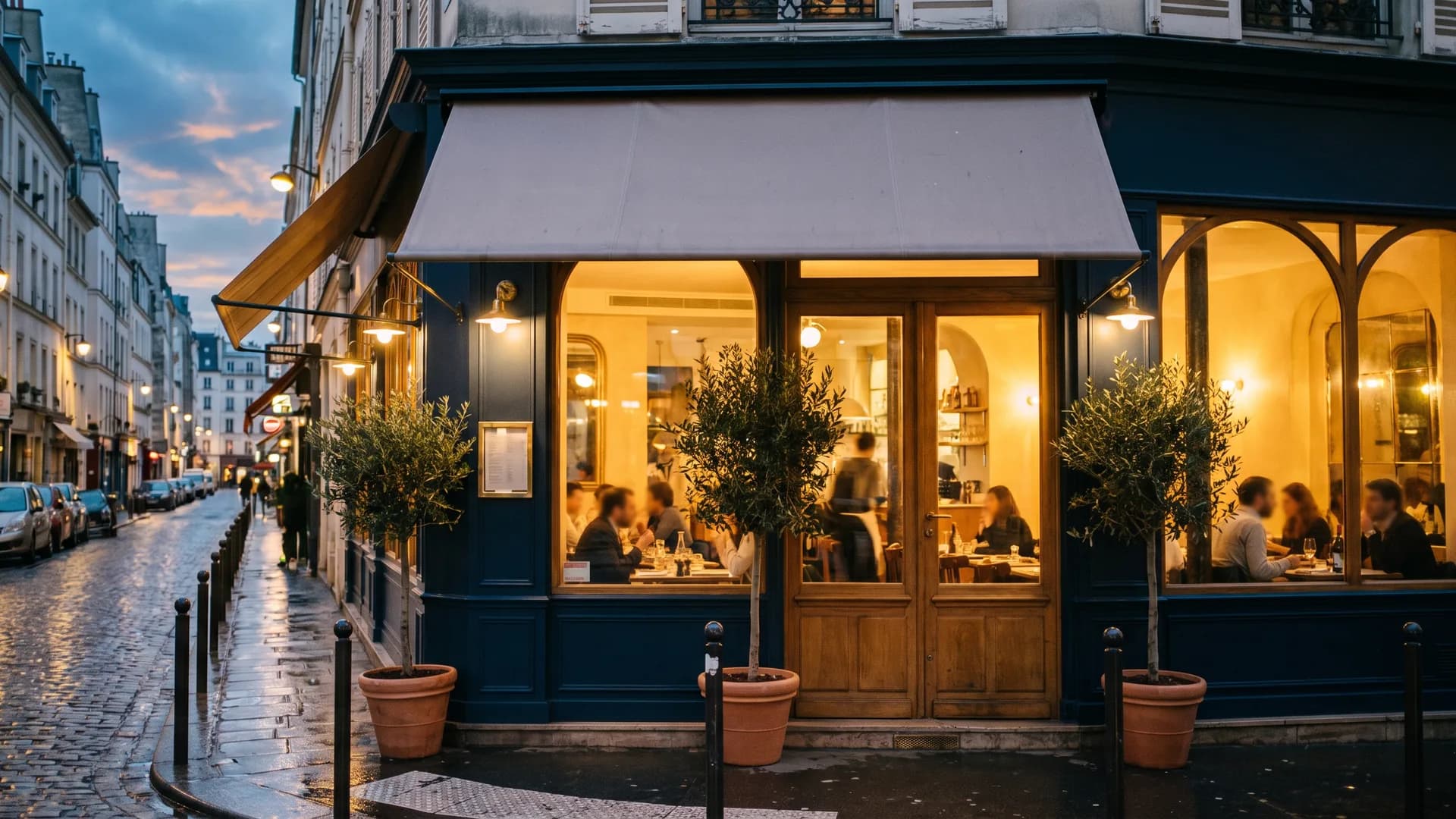 A neighborhood bistro at dusk with warm light in the windows